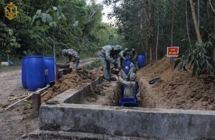 “Không để kéo dài qua mùa mưa, chất độc sẽ ảnh hưởng đến môi trường và cuộc sống người dân. Chúng tôi làm liên tục, chỉ có ngày chủ nhật mới nghỉ, có hôm làm đến 21-22g, cứ làm 60 phút lại nghỉ 30 phút để lấy lại sức. Mỗi lần uống nước thì ra khu vực nhà cách ly. Khi ăn phải tiêu tẩy sơ bộ, tắm rửa rồi ra khu vực khác cách ly với khu vực đang xử lý để ăn uống”, anh Thắng nói. Nguồn ảnh: Báo Quân đội Nhân dân