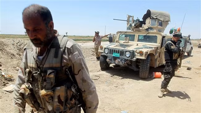 Chiến binh dân quân và binh sĩ quân đội đứng cạnh chiếc xe thiết giáp HMMWV của Mỹ cung cấp.