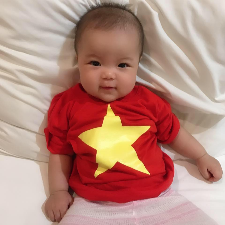 Nhóc tì này cũng diện áo cờ đỏ sao vàng để cổ vũ bố thi đấu trên sân cỏ.