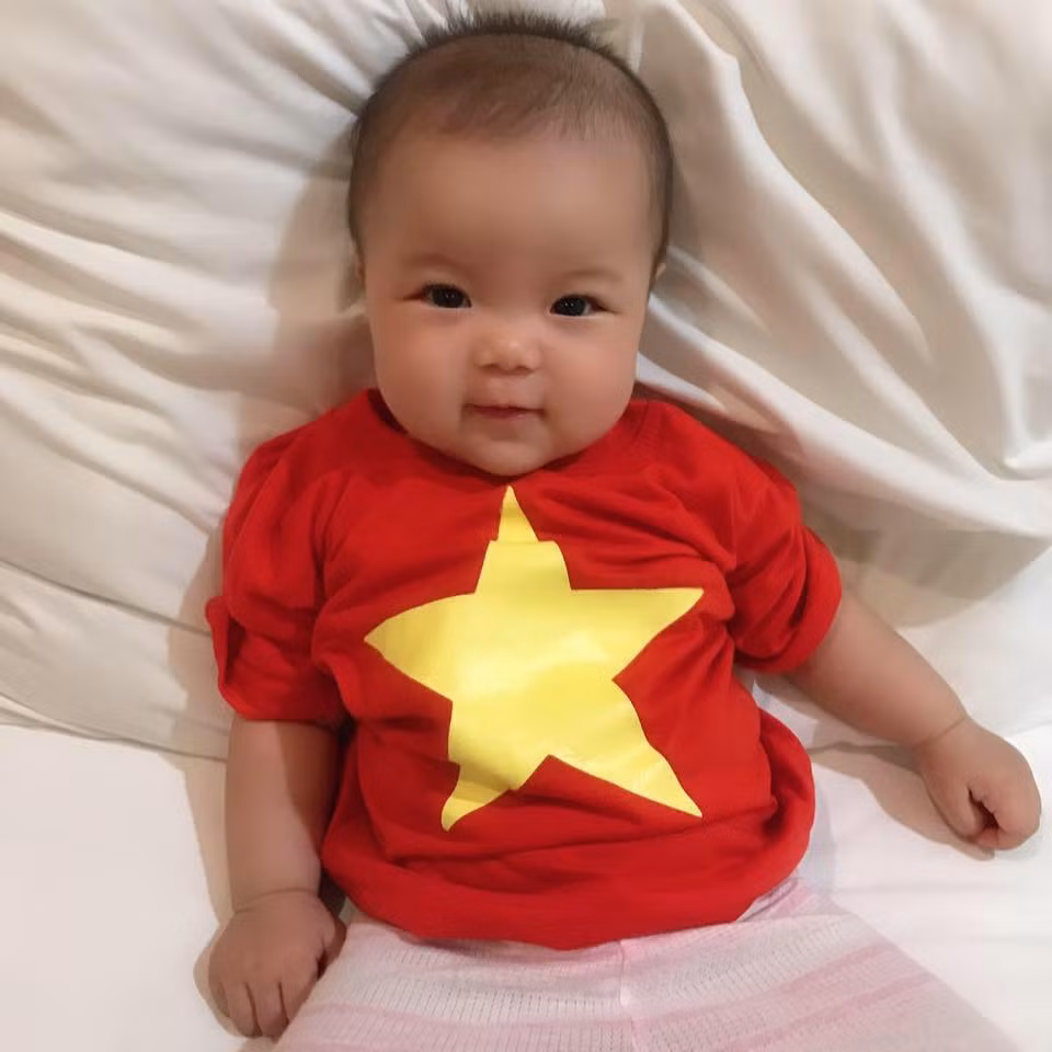 Nhóc tì này cũng diện áo cờ đỏ sao vàng để cổ vũ bố thi đấu trên sân cỏ.