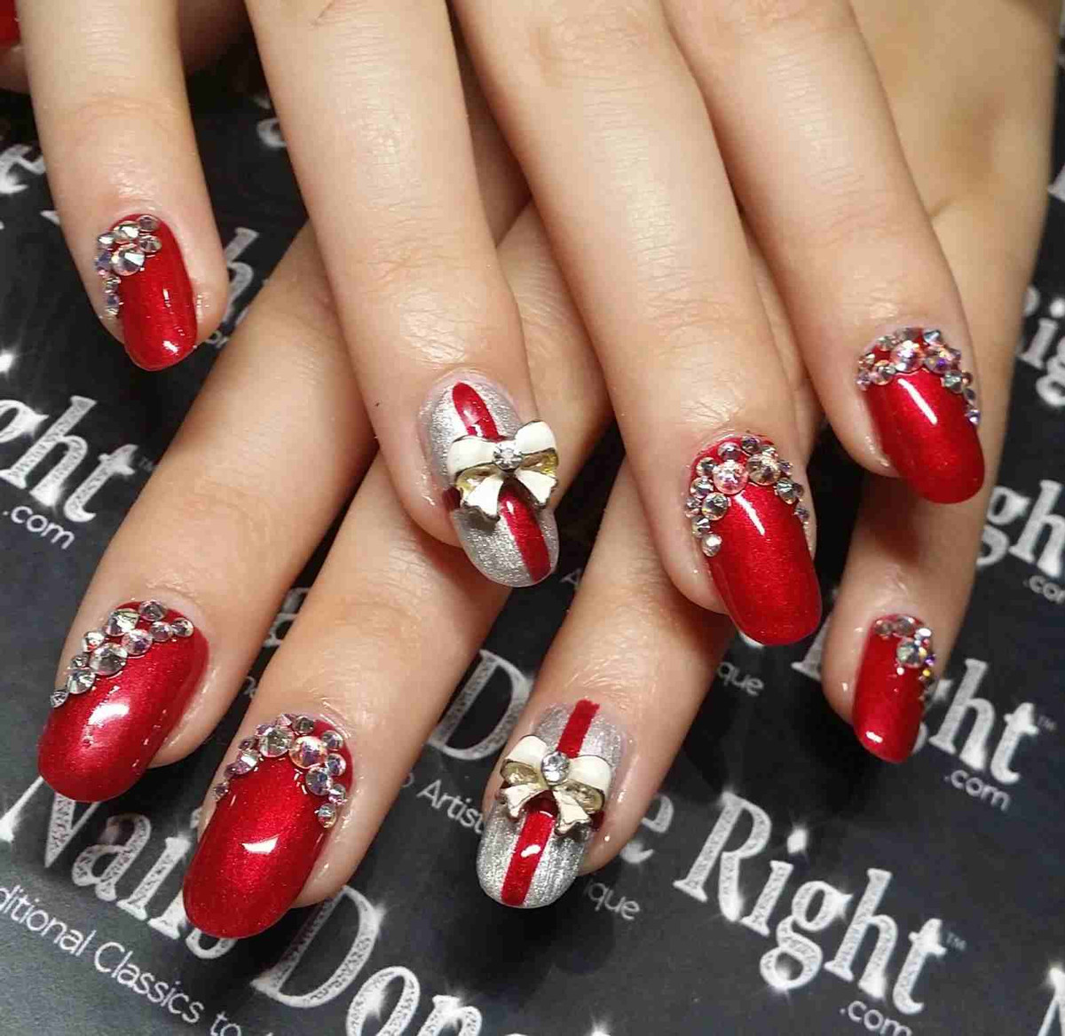 Bộ nail đỏ đính đá, hoặc nơ giống như những hộp quà Noel xinh xắn.
