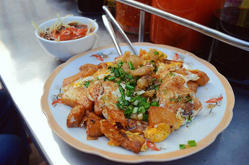 Các miếng bột được chiên cùng trứng và mỡ hành trên chảo, trông ngon mắt, ăn kèm nước tương và đồ chua. Xe bột chiên nổi tiếng nhất Sài Gòn nằm ở dọc đường Trần Đình Xu (quận 1), ngoài ra bất kỳ khu vực gần cổng trường, công viên đều có. Giá một đĩa bột chiên khoảng 15.000 đồng. Ảnh: Ivivu.