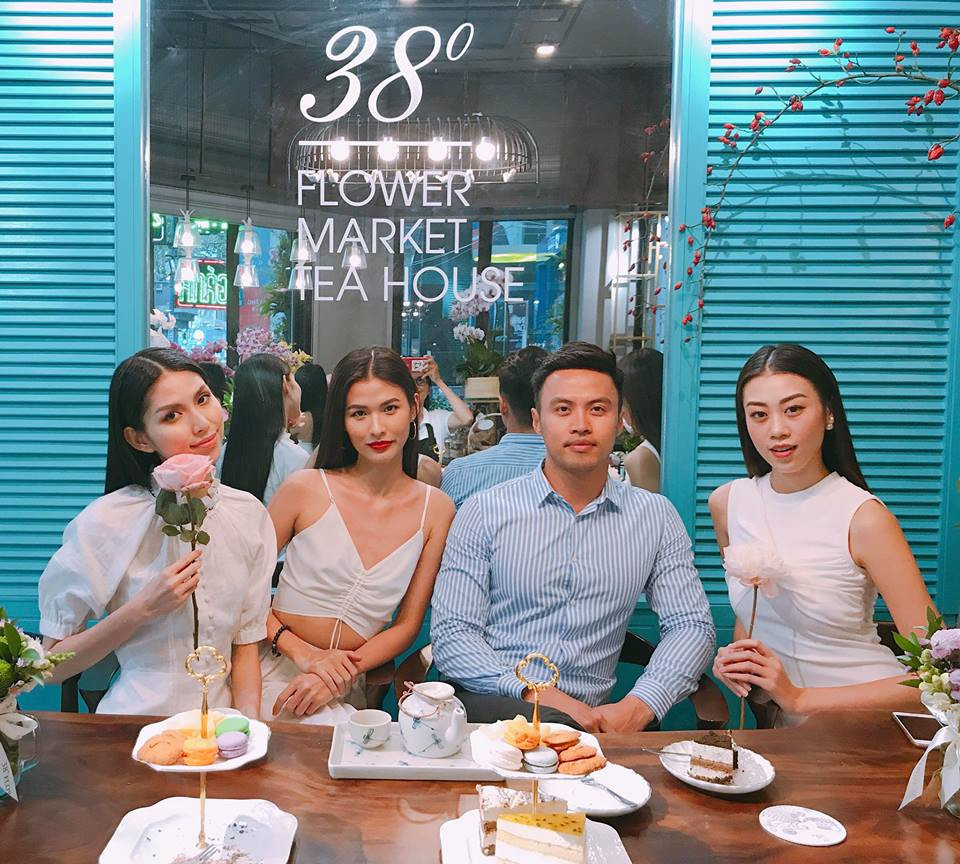 Shark Khoa mặc áo sơ mi xanh điển trai ngồi giữa các người đẹp.