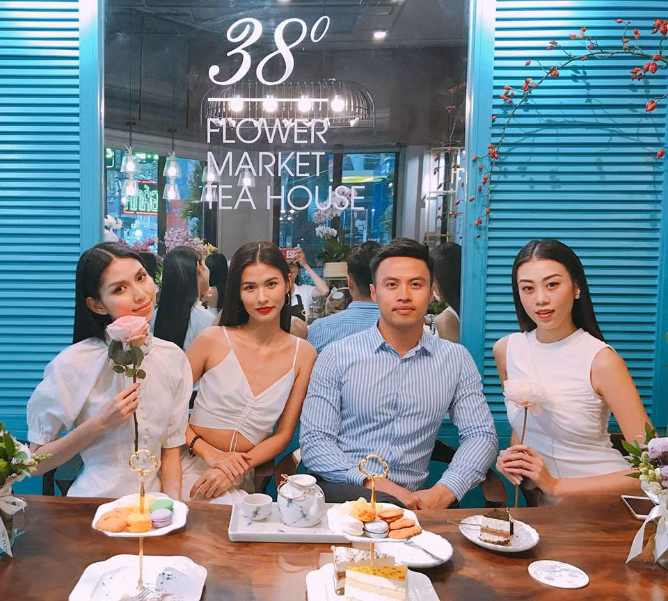 Shark Khoa mặc áo sơ mi xanh điển trai ngồi giữa các người đẹp.