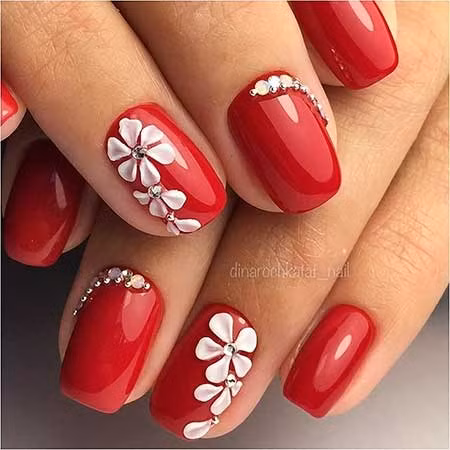 Mẫu nail đỏ đính đá hình bông hoa vừa nổi bật vừa nữ tính.