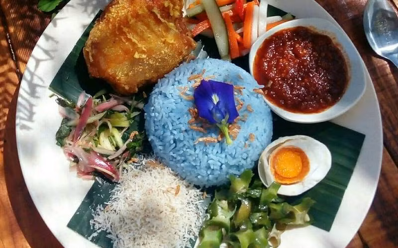 Món Nasi kerabu nổi tiếng nhanh chóng thu hút sự chú ý của thực khách nhờ vào bài trình bày đầy màu sắc của nó. Các món ăn thường được phục vụ với gà rán, nhiều dưa chua và keropok giòn (phồng tôm). Điểm nổi bật của món ăn là cơm được nhuộm màu xanh nhờ những cánh hoa Smurfs. 
