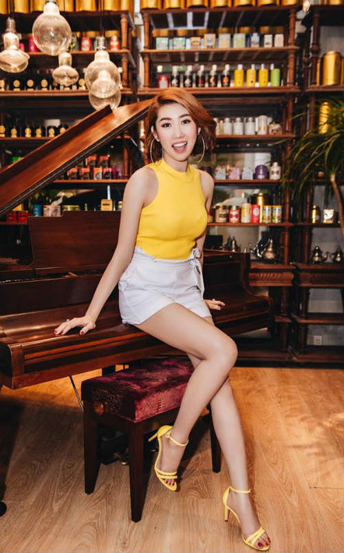 Chiếc áo sát nách vàng phối với váy trắng ngắn và đôi guốc vàng khá hợp tông.