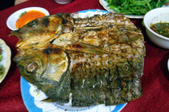 Hỗn hợp để tẩm ướp gồm mắc khén, ớt tươi nghiền nát, hành tươi, rau thơm, rau mùi thái nhỏ...trộn đều rồi nhồi vào bụng cá. Sau đó, cá được gập đôi lại rồi dùng nẹp tre nẹp cá nướng lên than hồng. Ảnh: Tuổi Trẻ.