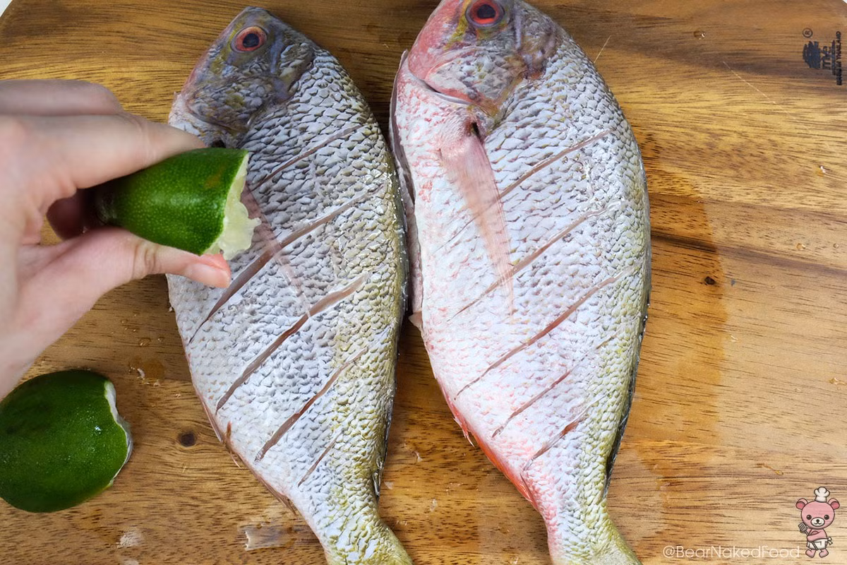 Cách làm món cá nướng: Làm sạch và lau khô cá, cắt vài đường sâu trên thân cá, vắt chanh lên để khử mùi tanh.