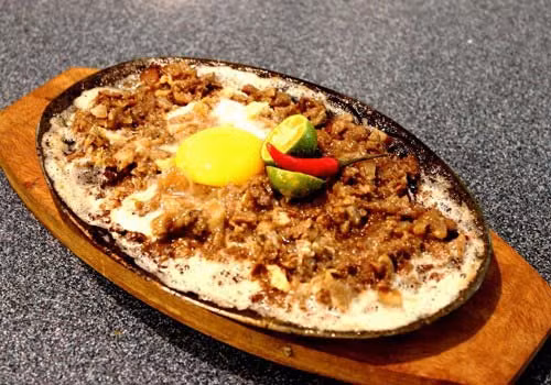 Sizzling Sisig là món đầu heo sau khi chế biến được phục vụ trên một đĩa sắt nung nóng.