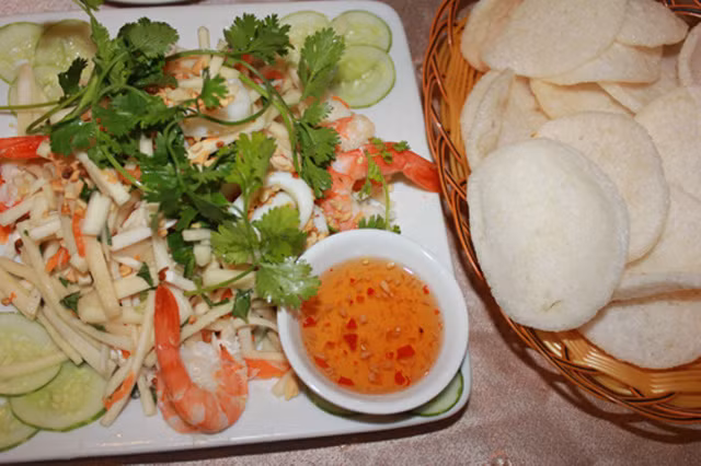 Phần củ hũ trắng muốt được bào mỏng, trộn với tôm luộc, thịt heo, tai heo thái mỏng, rau răm, đậu phộng rang và nước sốt chua ngọt. Đĩa gỏi củ hũ dừa có cả “thanh lẫn sắc”, đẹp mắt ngon miệng, ăn kèm bánh phồng tôm giòn giòn.