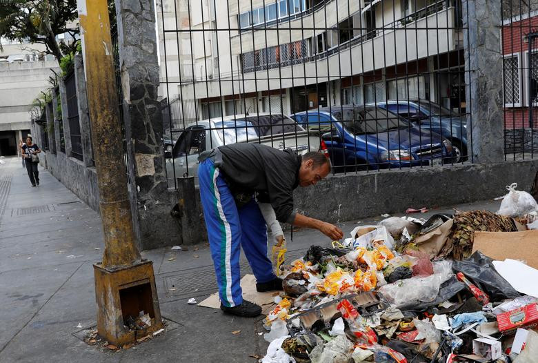 Người đàn ông tìm đồ ăn trong bãi rác ở Caracas ngày 26/2.
