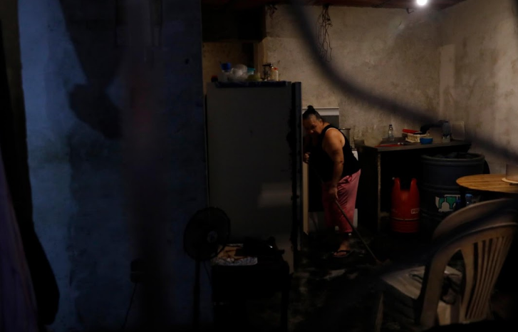 Minerva Savago, 58 tuổi, lau sàn nhà trong căn phòng tối.