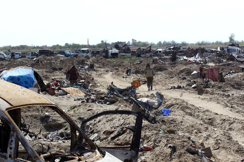 Một thành viên SDF đi qua ngôi làng Baghouz bị tàn phá vì chiến tranh hôm 23/3.