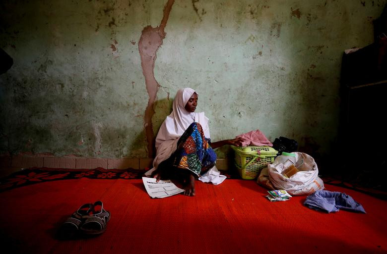 Adama Mustapha, mẹ của Salamutu, Fatima và Maryam Mustapha - những nữ sinh bị mất tích của trường Khoa học và Kỹ thuật dành cho nữ giới, ngồi cạnh quần áo và vật dụng của các con gái bà trong ngôi nhà ở Dapchi, phía đông bắc Yobe, Nigeria, ngày 24/2/2018. Mời độc giả xem thêm video: Người phụ nữ thấp nhất thế giới "tỏa sáng" ở New York (Nguồn: VTC14)