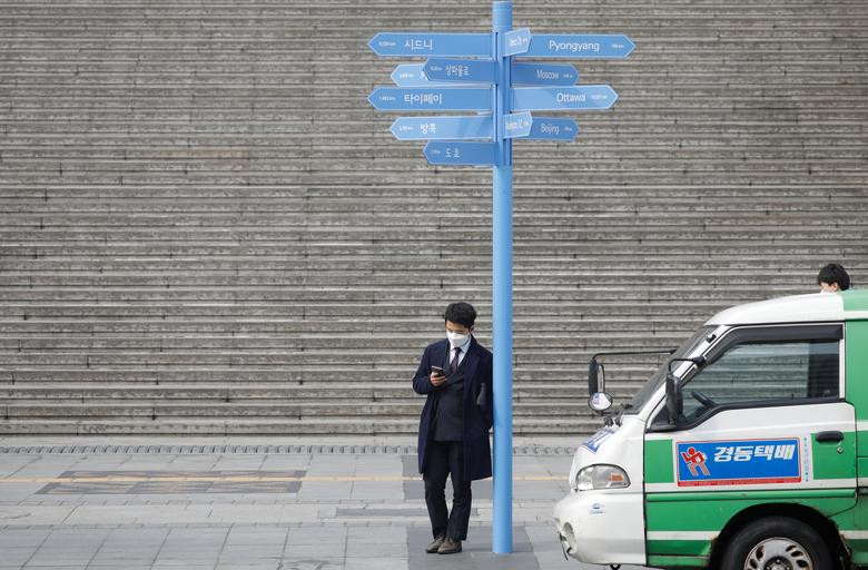 Người đàn ông đeo khẩu trang khi đứng chờ trên đường phố Seoul hôm 5/3.