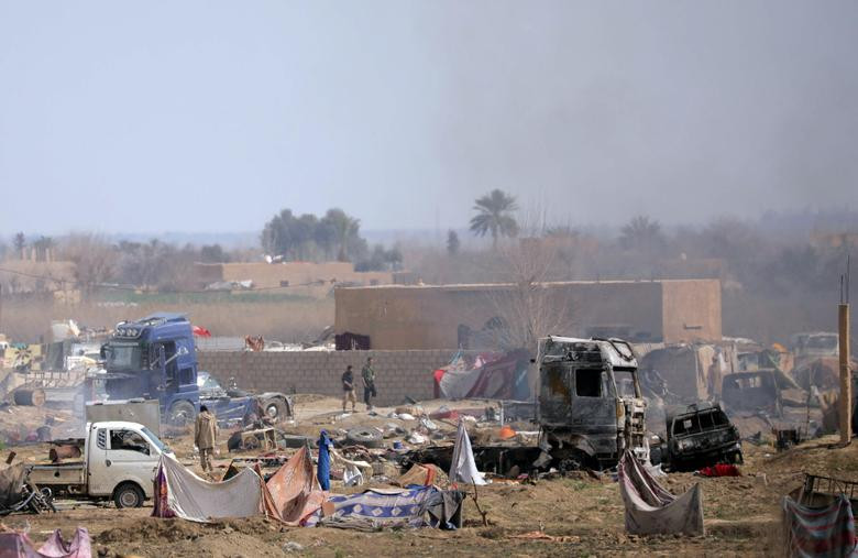 Các thành viên IS đi bộ tại khu vực bị bao vây ở ngôi làng Baghouz ngày 10/3. Ảnh: Reuters.