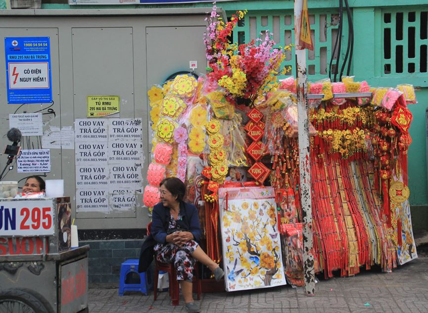 Nhiều vật phẩm trang hoàng ngày Tết như cành mai, cành đào, hoa dán tường, bao lì xì, câu chúc tốt lành... đã được bày bán trên nhiều tuyến đường trung tâm thành phố như Hai Bà Trưng, Võ Thị Sáu, Ba tháng Hai...
