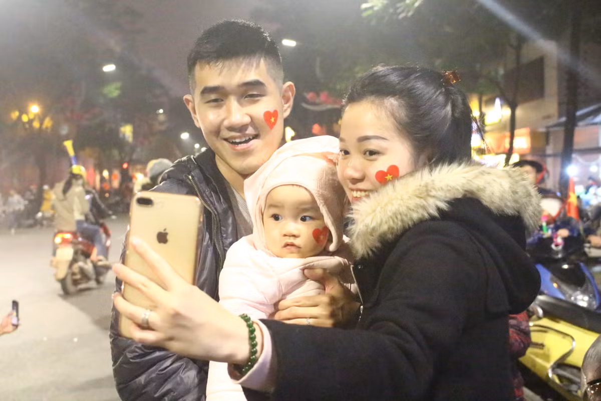 Một gia đình nhỏ hòa mình vào không khí rộng ràng cờ hoa và âm thanh của đêm "đi bão".