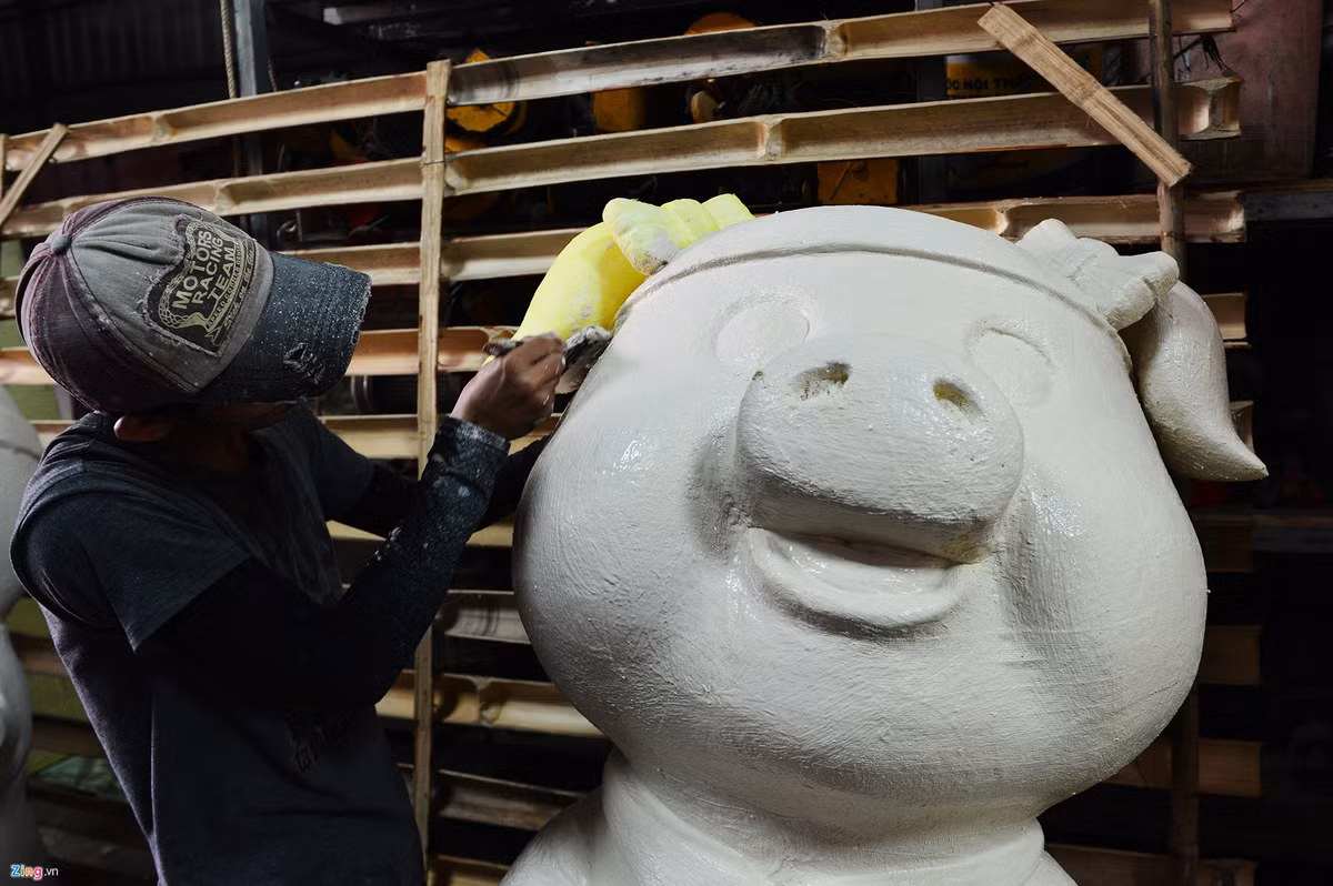 Những chú heo được tạo hình bằng xốp, sau đó sẽ được phủ các lớp màn, tiếp tục quét xi măng trắng, sơn màu, vẽ họa tiết và làm mịn trước khi mang ra trưng bày.