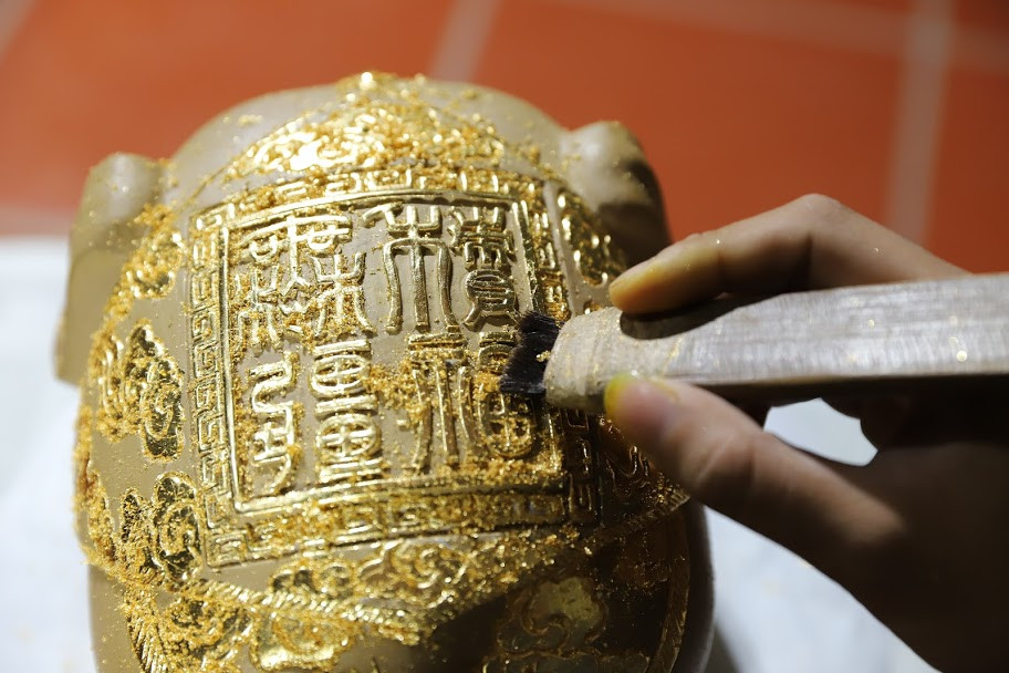 Nghệ nhân làng Kiêu Kỵ Dát vàng lên hoa văn và nét chữ.