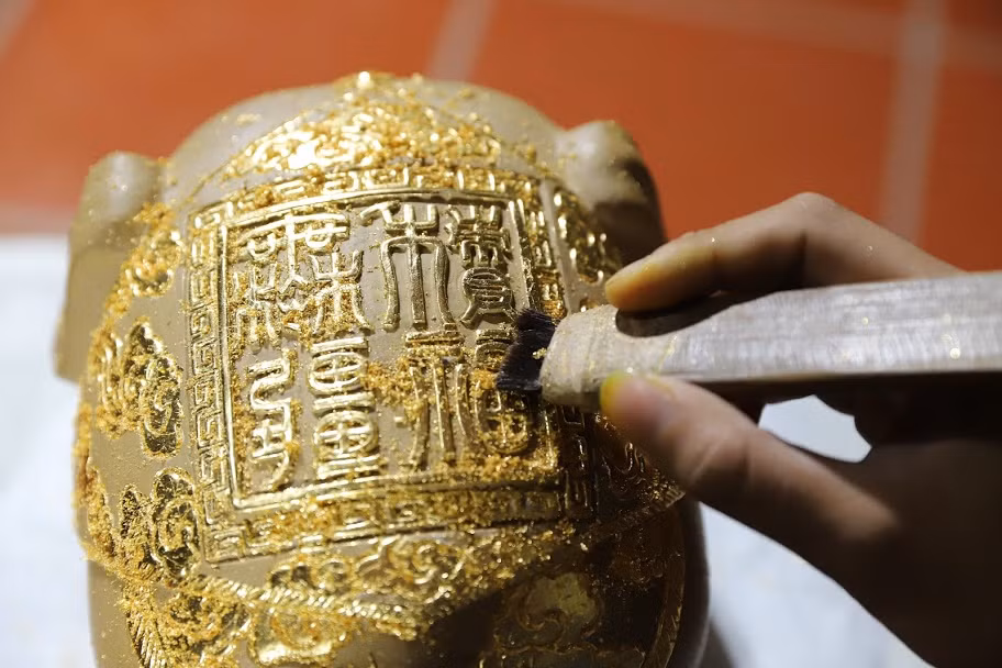 Nghệ nhân làng Kiêu Kỵ Dát vàng lên hoa văn và nét chữ.