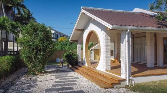 Khoảng sân cỏ rộng phía trước nhà có những cây gỗ lớn, tán rộng, đủ bóng râm mát cho con trẻ nô đùa, tối đến thì gia đình có thể tụ họp.