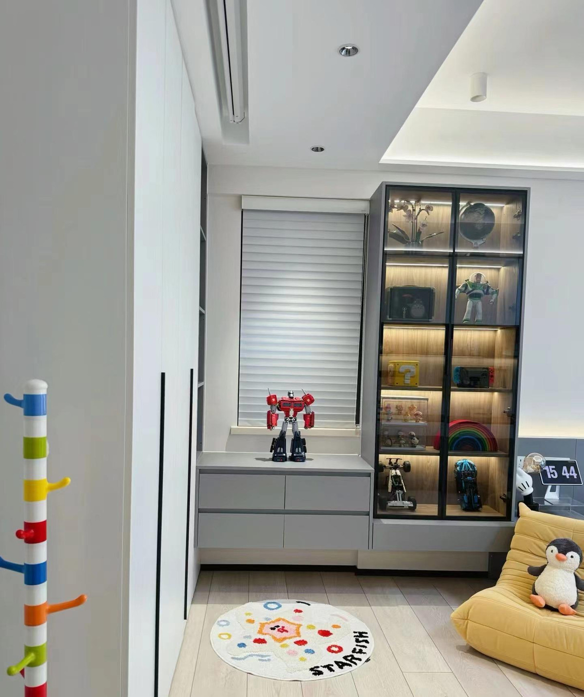 Vì căn phòng được sử dụng cho 2 bé nên nguyên tắc trang trí là phải làm thế nào để có thêm chỗ chứa đồ. Ngoài một dãy tủ âm tường, một tủ đựng đồ nổi cũng được bố trí ở đầu giường. 