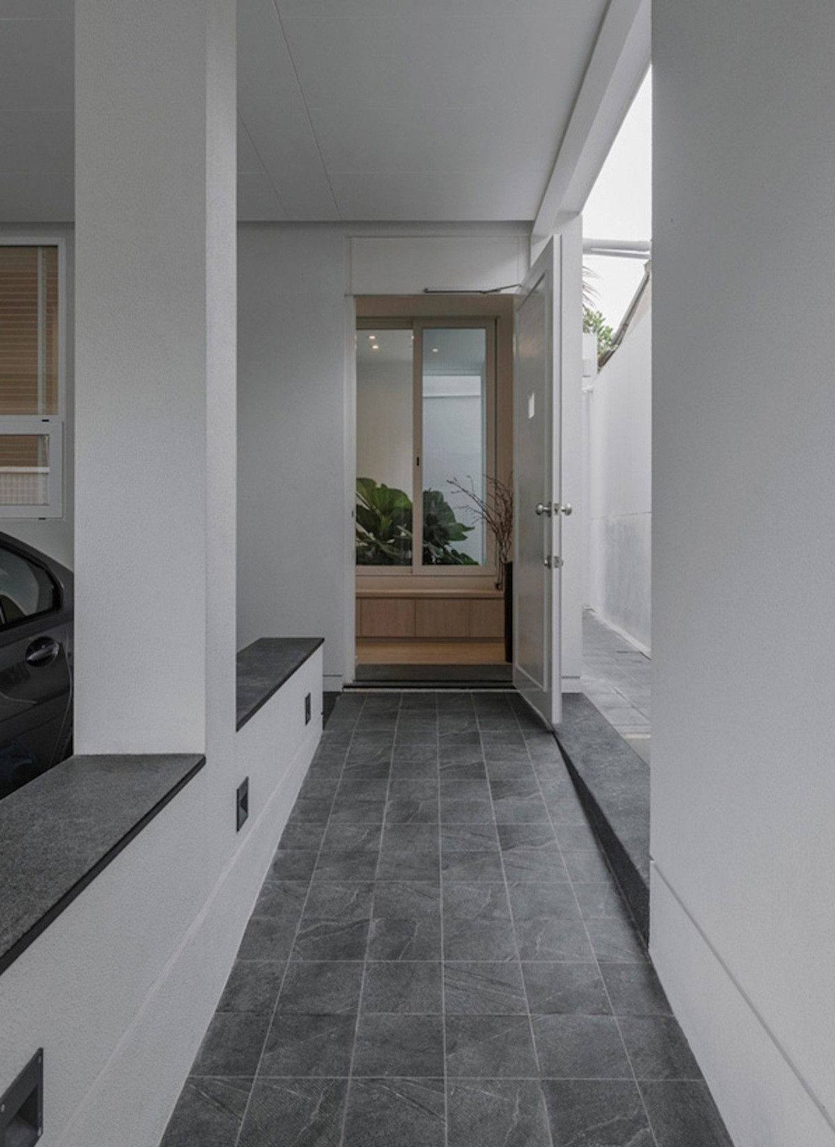 Mặt tiền của căn nhà được xây dựng thoáng với các ô cửa, lùi vào phía sau để có không gian phía trước tầng 2 làm khu vườn và đặt chậu cây xanh. Căn nhà nằm trên khu đất 220m2 với 3 tầng. Trong đó khoảng phía trước tầng 1 được gia chủ tận dụng làm nơi đỗ xe. 