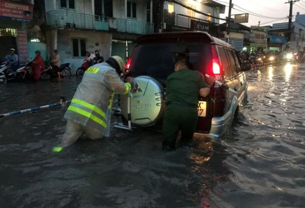 Lực lượng chức năng đang giúp một chiếc ô tô di chuyển qua đoạn đường ngập.