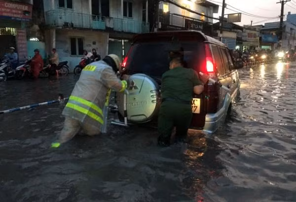 Lực lượng chức năng đang giúp một chiếc ô tô di chuyển qua đoạn đường ngập.