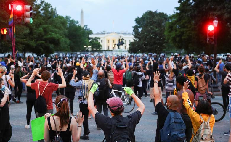 Nhiều người biểu tình giơ tay trước hàng rào cảnh sát sau cuộc đụng độ tại Công viên Lafayette.