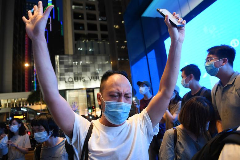 Người đàn ông đeo khẩu trang giơ tay lên cao trong cuộc biểu tình tại khu Central ở Hong Kong ngày hôm qua.