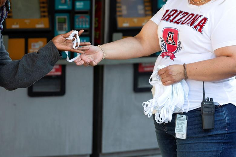 Nhân viên của Sun Tran phát khẩu trang miễn phí cho hành khách tại bến xe buýt ở Tucson, bang Arizona, ngày 20/6.