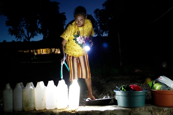 Noti hứng nước vào các bình khi chuẩn bị bữa tối bên ngoài ngôi nhà của cô.