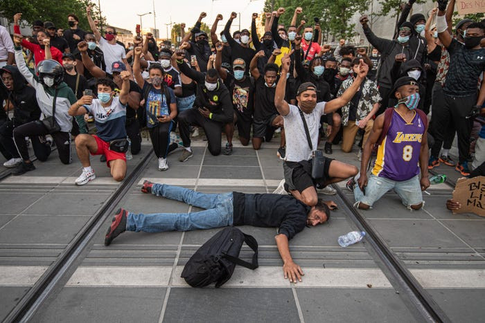 Những người biểu tình tại Paris quỳ gối và giơ nắm đấm phản đối hành vi bạo lực của cảnh sát.