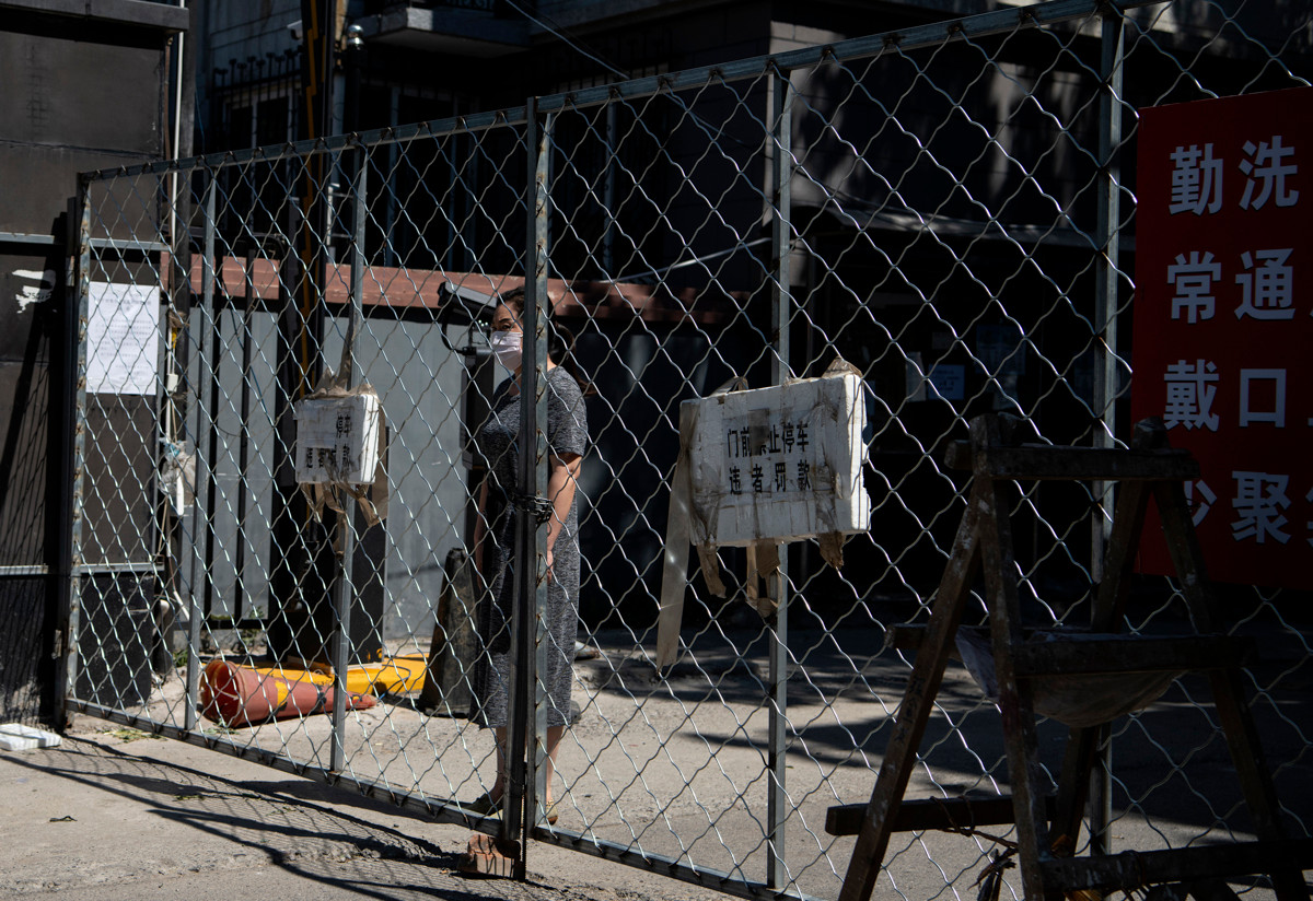 Một phụ nữ ở Yilanyuan chờ nhận đồ ăn đặt trên mạng sau khi nơi này bị phong tỏa vì các ca nhiễm COVID-19 mới được phát hiện liên quan đến chợ đầu mối nông sản Tân Phát Địa. Ảnh: AJ.