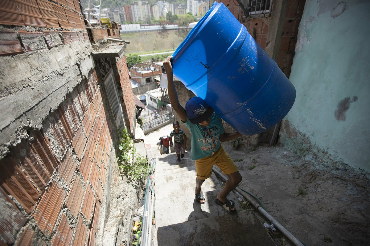 Em nhỏ mang thùng đi lấy nước trong khu dân cư Petare ngày 15/6.