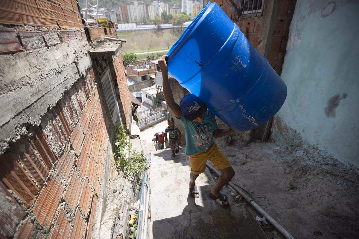 Em nhỏ mang thùng đi lấy nước trong khu dân cư Petare ngày 15/6.