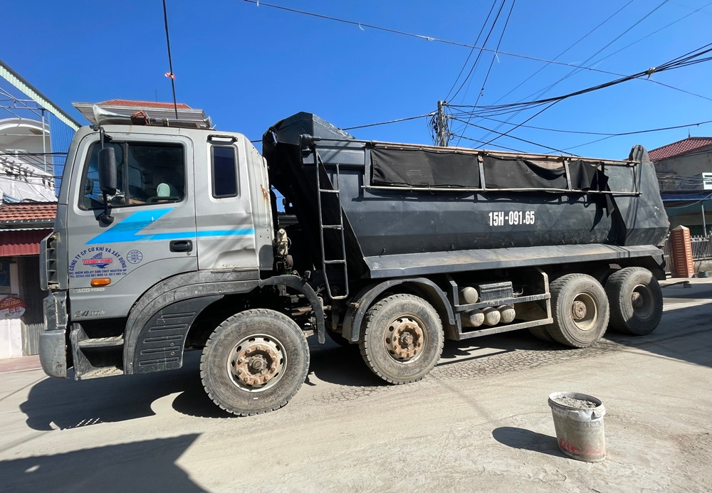 Hai bên lòng đường, người dân đặt một số thùng nhựa đổ bê tông bên trong để hạn chế các xe tải va quệt vào nhà cửa. Bến bãi có bố trí xe tưới nước để giảm bụi trên tuyến đường nhưng ăn thua.