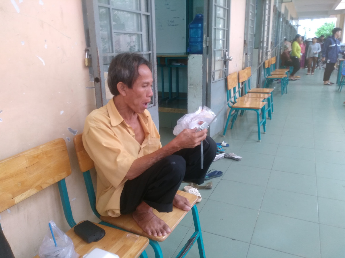 Người đàn ông vừa ăn bánh vừa nghe Radio để cập nhật tình hình về cơn bão số 9. 