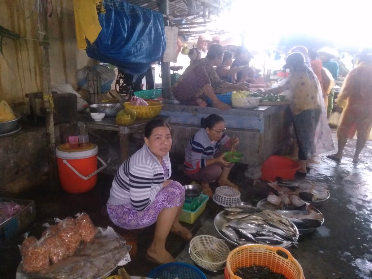 Hàng chục tiểu thương và người dân bình thản ngồi ở chợ đón cơn bão số 9. 