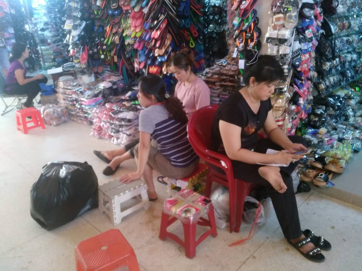 Vì vắng bóng người mua, nên các tiểu thương chợ Bình Tay dùng điện thoại để giải khuây.