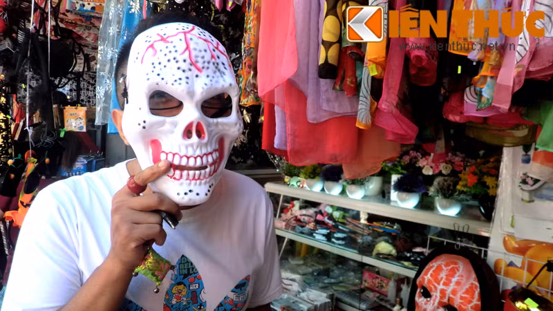 Một khách hàng nam đang thử mặt nạ tại cửa hàng lưu niệm trên phố Nghĩa Tân (Cầu Giấy).