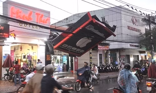 Thoạt nhìn tưởng như biển quảng cáo đu dây điện chơi ngông, thực chất đây là hậu quả sau một cơn bão khiến tấm biển bị đổ, vướng vào dây điện khá nguy hiểm.