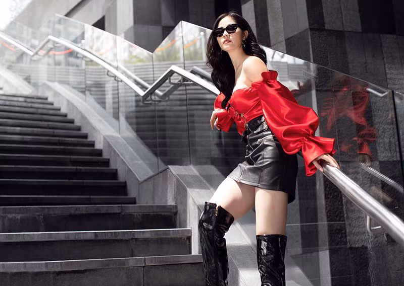 Áo đỏ trễ vai cách đệu phối với chân váy da màu đen giúp Hoàng Hạnh nổi bật mọi nơi.