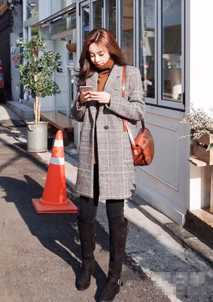 Áo len cao cổ mix cùng áo khoác kẻ dáng dài tạo nên phong cách thanh lịch. Đôi bốt cao cổ là phụ kiện thích hợp cho set đồ này.