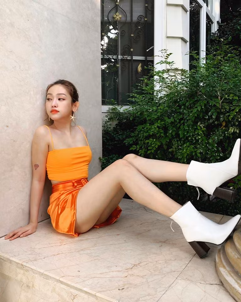 Mix đồ gam màu cà rốt nổi bật cho dịp cuối năm, Thúy Vi tạo điểm nhấn bằng đôi boot cổ thấp màu trắng.