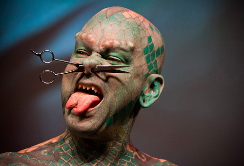 Trẻ con sẽ khóc thét khi chứng kiến người đàn ông với lớp da xăm xanh đỏ như rắn, lưỡi chẻ, u sần vùng lông mày cùng tạo hình chiếc khuyên là một cái kéo.