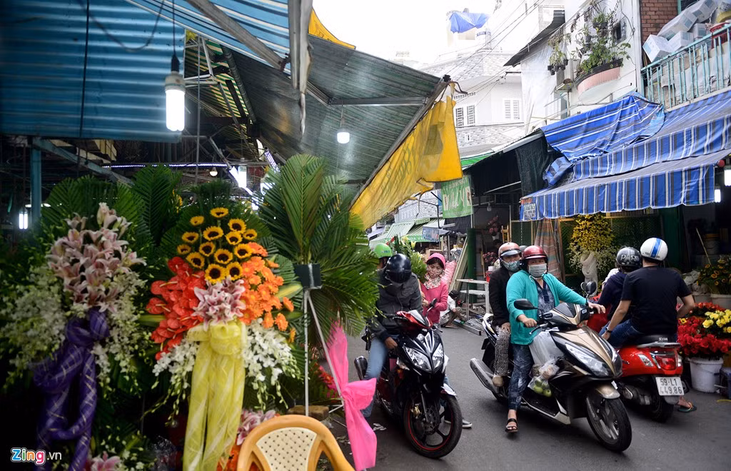 Các chủ sạp cơi nới mái che ra giữa tim đường, đồng thời đặt những lãng hoa chiếm ngay phần không gian phía dưới khiến phần đường dành cho xe cộ, người đi bộ qua lại bị thu hẹp.